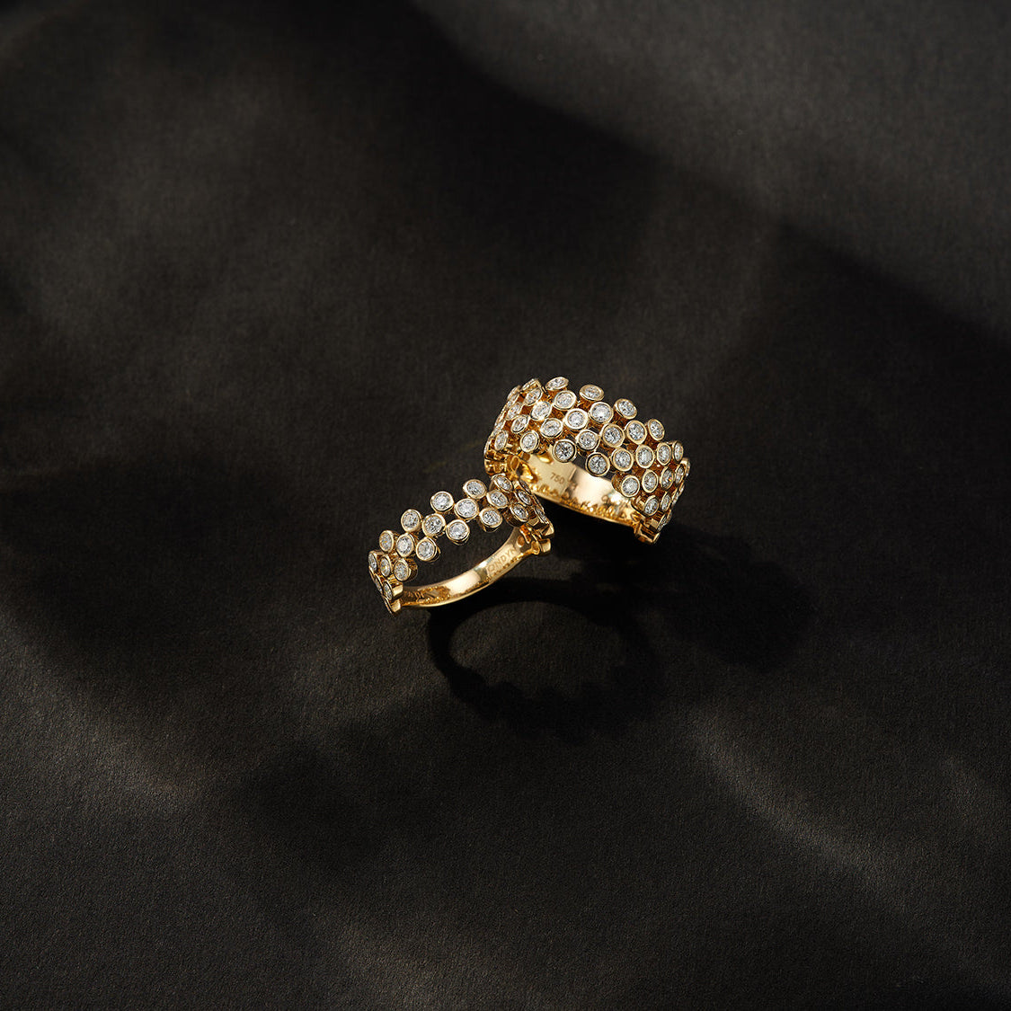Two 18kt gold rings with natural diamonds on a black background
